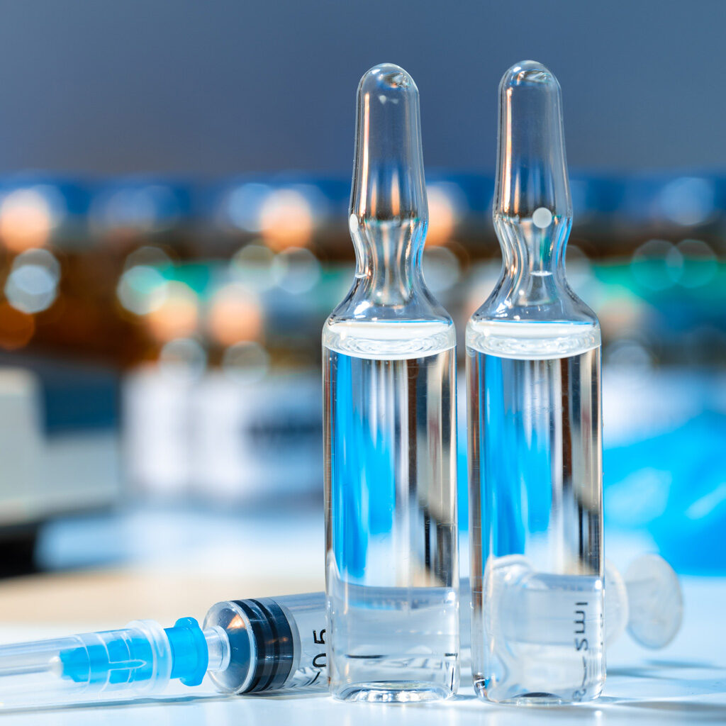 Close picture of two vials and a syringe on a laboratory table. Aseptic processes vs non-sterile processes. Examples of medical products manufactured in aseptic environments. Examples of medical products manufactured in non-sterile environments. Pharmaceutical sterile products. Best sterilization process for your medical device