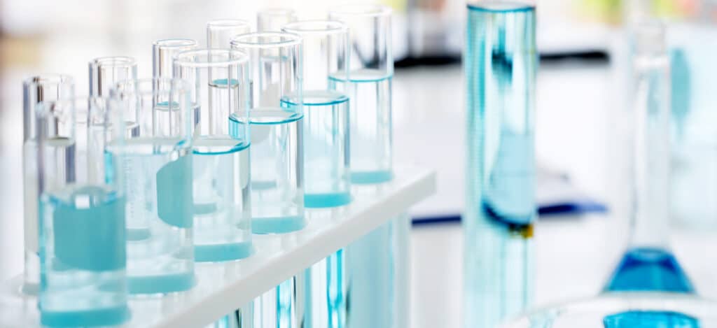 Picture of several test tubes with blue liquid inside in a white laboratory background. Preservative efficacy testing vs sterility testing. Differences between preservative efficacy testing and sterility testing. Why is sterilization essential for medical products and devices. How are sterility tests performed. Bioburden-biological indicator sterilization